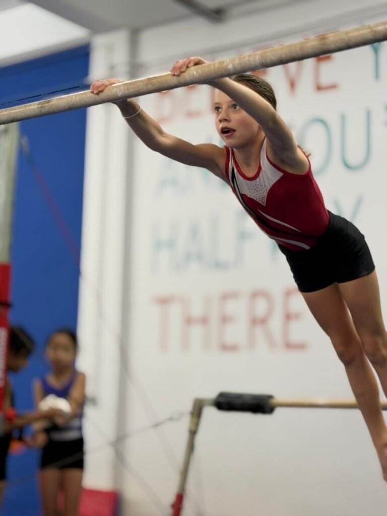 Young gymnast practicing on the uneven bars at Flykidz Gymnastics in Petaling Jaya, showcasing kids gymnastics programs.