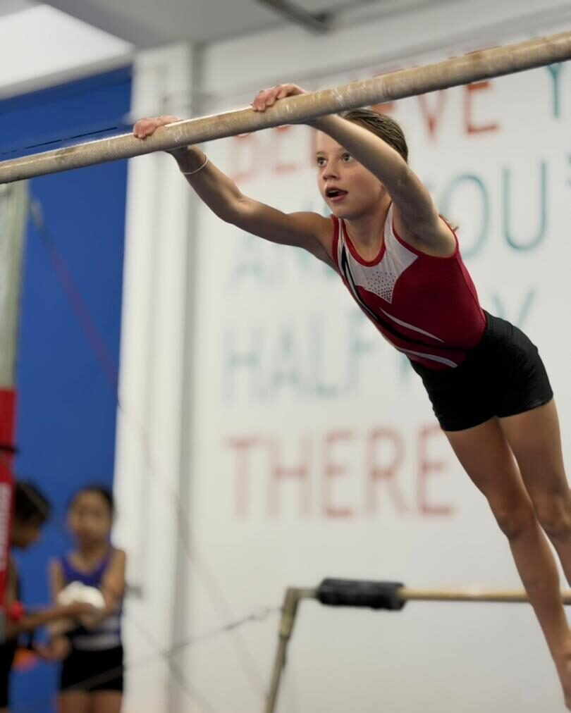 Young gymnast practicing on the uneven bars at Flykidz Gymnastics in Petaling Jaya, showcasing kids gymnastics programs.
