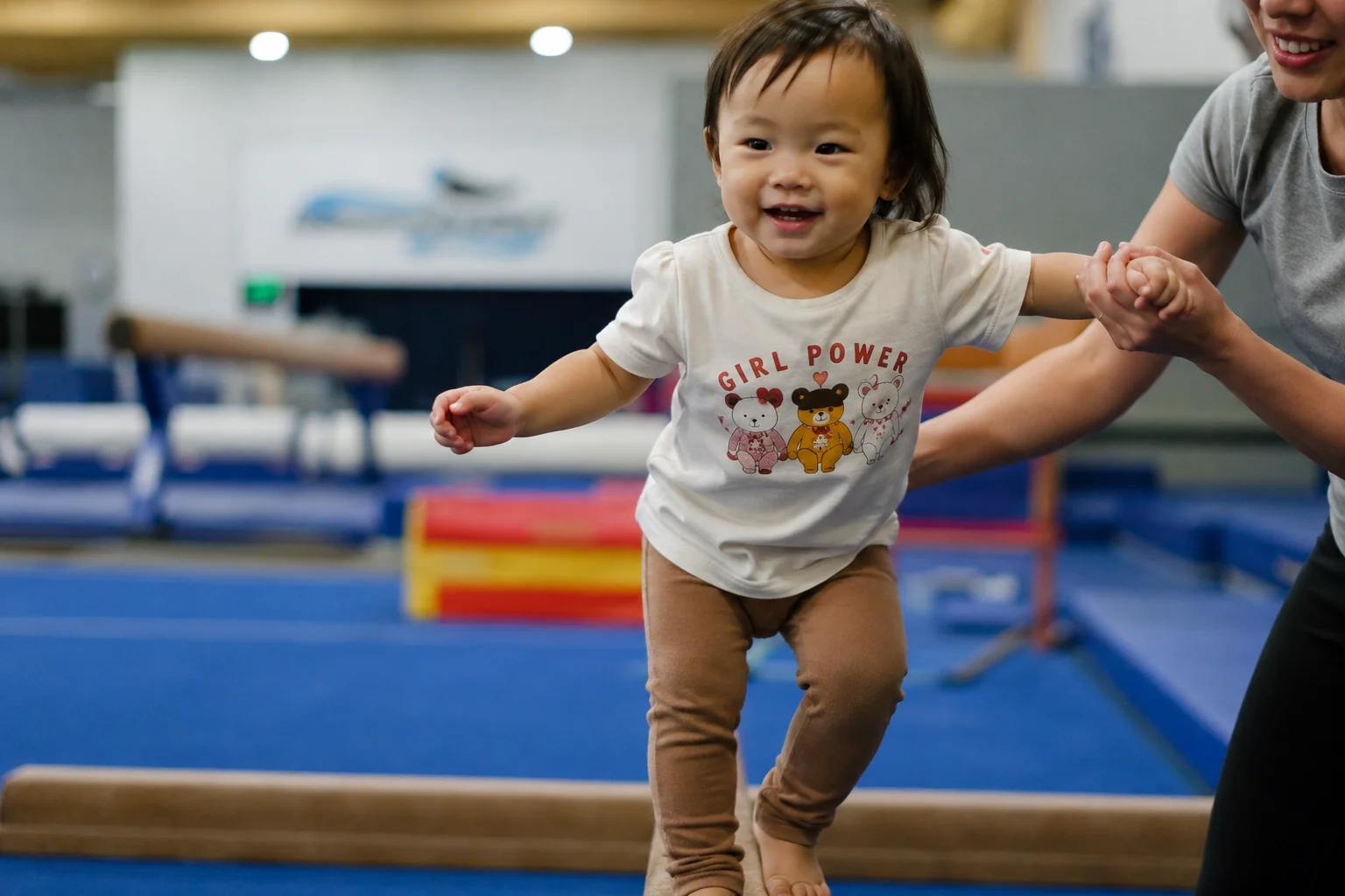 Toddler girl walking on balance beam at Flykidz gymnastics, Petaling Jaya, coached by instructor